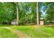 Lush backyard featuring a playground set, storage shed and mature trees that create a perfect play and relaxation area at 3315 Swepsonville Saxapahaw Rd, Graham, NC 27253
