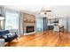 Inviting living room featuring hardwood floors, a brick fireplace, and a view of the kitchen with modern cabinets at 3315 Swepsonville Saxapahaw Rd, Graham, NC 27253