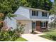 Charming two-story home featuring a brick facade, blue door, landscaped yard, and an attached one car garage at 505 Drolmond Dr, Raleigh, NC 27615