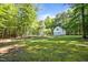 Backyard shot shows this home surrounded by trees, a green lawn, and a large garage at 5216 Woods End Rd, Hillsborough, NC 27278