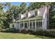 Charming white home featuring a welcoming front porch, dormer windows, and a lush landscaped yard at 5216 Woods End Rd, Hillsborough, NC 27278
