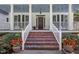 Inviting front porch with red brick stairs, stately columns, and space for seating, framed by lush greenery at 5216 Woods End Rd, Hillsborough, NC 27278