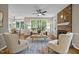 Bright living room with brick fireplace, large windows, ceiling fan, and hardwood floors at 5216 Woods End Rd, Hillsborough, NC 27278