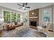 Cozy living room with brick fireplace, large windows, ceiling fan, and stylish furnishings at 5216 Woods End Rd, Hillsborough, NC 27278