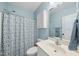 Light and airy bathroom with blue walls, decorative shower curtain, and classic white vanity and mirror at 55 Kristopher Woods Dr, Youngsville, NC 27596