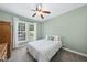 Cozy bedroom with neutral carpet, calming green walls, ceiling fan, and bright window with white curtains at 55 Kristopher Woods Dr, Youngsville, NC 27596