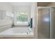 This main bathroom boasts a soaking tub, glass block window, and tiled shower at 55 Kristopher Woods Dr, Youngsville, NC 27596