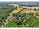 Aerial view showing proximity to farmland, the home, outbuildings, and its secluded, wooded surroundings at 6022 Little Creek Church Rd, Clayton, NC 27520