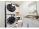 Functional laundry room with stacked washer/dryer and a sink and white cabinets at 6022 Little Creek Church Rd, Clayton, NC 27520
