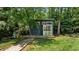 Modern backyard studio with minimalist design, a wooden deck, large glass door, and surrounded by lush greenery at 7309 Forest Glade Ct, Raleigh, NC 27615