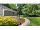 Landscaped backyard with a concrete pathway, studio, and green lawn, offering a serene outdoor space at 7309 Forest Glade Ct, Raleigh, NC 27615