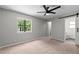 Neutral bedroom boasts a ceiling fan, large window and adjacent full bathroom at 7309 Forest Glade Ct, Raleigh, NC 27615