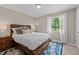Comfortable bedroom with wooden bed frame, soft rug, and natural lighting at 7309 Forest Glade Ct, Raleigh, NC 27615