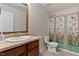 Functional bathroom features a wood vanity, toilet, and shower with curtain at 8005 Caithness St, Raleigh, NC 27616