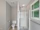 Modern bathroom featuring a glass-enclosed shower, white toilet, and natural light from the window at 8640 Swarthmore Dr, Raleigh, NC 27615