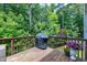 Spacious wooden deck featuring a grill and flowerpots surrounded by lush trees at 8715 Macedonia Lake Dr, Cary, NC 27518