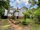 A backyard shows a two-story house with peeling paint, steps leading to the upper level, and lush greenery at 94 Bynum Church Rd, Pittsboro, NC 27312