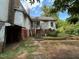 A backyard shows a two-story house with peeling paint, a partially collapsed room, and lush greenery at 94 Bynum Church Rd, Pittsboro, NC 27312