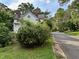 Exterior view of home partially obscured by lush landscaping next to a quiet street at 94 Bynum Church Rd, Pittsboro, NC 27312