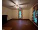 A spacious living room has a ceiling fan, two windows with curtains, and dark painted floors at 94 Bynum Church Rd, Pittsboro, NC 27312