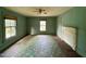 A living room is painted light green and features two large windows, a fireplace, and worn wood floors at 94 Bynum Church Rd, Pittsboro, NC 27312