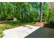 Backyard featuring a concrete patio and a lush lawn that is surrounded by mature trees and plants at 102 Emerald Cir, Durham, NC 27713