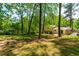Backyard with a green lawn, mature trees, seating area with a fire pit, and surrounded by lush greenery at 102 Emerald Cir, Durham, NC 27713