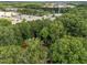 An aerial view from a high angle shows a property surrounded by lush trees and nearby buildings in the distance at 1040 Ivy Ln, Cary, NC 27511