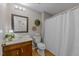 Bright bathroom with wood floor, a classic vanity and mirror, and a shower with white shower curtain at 1040 Ivy Ln, Cary, NC 27511