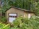 Rustic garage with a white door framed by lush greenery, offering privacy and charm at 1040 Ivy Ln, Cary, NC 27511