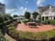 Outdoor brick patio with fire pit, benches, and built-in barbecue stations in a landscaped community with pool in background at 10511 Sablewood Dr # 107, Raleigh, NC 27617