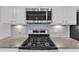 Close-up of a stainless steel range with microwave above granite countertops and white cabinetry at 10511 Sablewood Dr # 107, Raleigh, NC 27617
