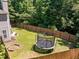 Large fenced backyard with lush green grass, a trampoline, and a fire pit area at 110 Bonhill Ct, Apex, NC 27502