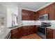 Well-lit kitchen featuring granite countertops, stainless appliances, and cherry cabinets at 110 Bonhill Ct, Apex, NC 27502
