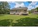 View of the house's rear facade with a wooden deck and stairs, set on a spacious lawn at 1203 First Street Ext, Nashville, NC 27856