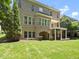 The rear of a two-story brick home with a covered patio and lush green backyard at 12257 Beestone Ln, Raleigh, NC 27614
