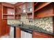 Attractive bar with a black countertop, mosaic backsplash, cabinets, and stainless steel dishwasher at 12257 Beestone Ln, Raleigh, NC 27614