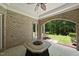 Covered patio with brick pillars, ceiling fan, stone table, and view of the landscaped yard at 12257 Beestone Ln, Raleigh, NC 27614