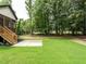 Home exterior featuring a grassy backyard with large trees and a concrete patio accessible from a wooden staircase at 1328 Bethlehem Church Rd, Youngsville, NC 27596