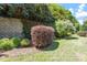 Well-maintained backyard featuring diverse plantings, a brick retaining wall, and manicured greenery at 1413 Lily Creek Dr, Cary, NC 27518