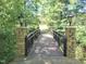 Stone and steel pedestrian bridge in a lush, wooded area of the community at 1413 Lily Creek Dr, Cary, NC 27518