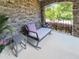 Close up of a cozy outdoor seating area on a covered stone porch with natural light and inviting furniture at 1413 Lily Creek Dr, Cary, NC 27518