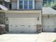 Attached two car garage featuring paneled doors, stone accents, and carriage lights at 1413 Lily Creek Dr, Cary, NC 27518