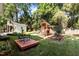 Wide angle view of backyard showing wooden playground, shed, patio and lush green lawn at 1811 Ridley St, Raleigh, NC 27608