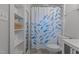 Well-lit bathroom with open shelving, toilet, and shower with decorative curtain at 1811 Ridley St, Raleigh, NC 27608