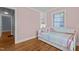 Bedroom with a window, built-in shelving, and hardwood floors leading to a doorway at 1811 Ridley St, Raleigh, NC 27608