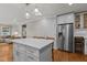 Open kitchen with a large island, stainless steel refrigerator, and modern white cabinets at 1811 Ridley St, Raleigh, NC 27608