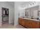 Bathroom with double sinks, granite countertop, wooden cabinets, a large mirror, and walk-in closet at 186 Ross Dr, Pittsboro, NC 27312