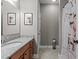 Well-lit bathroom featuring a granite countertop, wooden cabinets, and shower with decorative curtain at 186 Ross Dr, Pittsboro, NC 27312