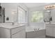 Bright bathroom featuring a corner tub, a large glass block window, and dual vanities at 1990 Ferbow St, Creedmoor, NC 27522